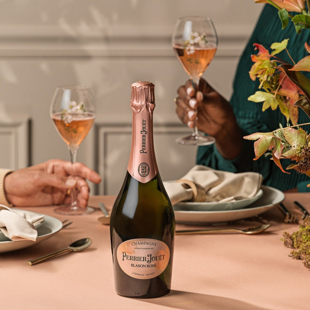 Champagne bottle on a table with people enjoying a meal in the background