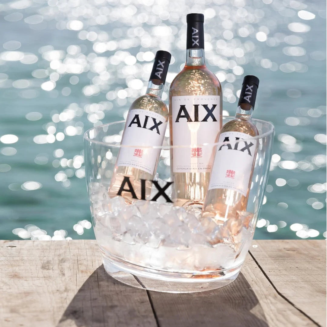 Load image into Gallery viewer, Three bottles of AIX wine in a glass ice bucket by a waterfront.