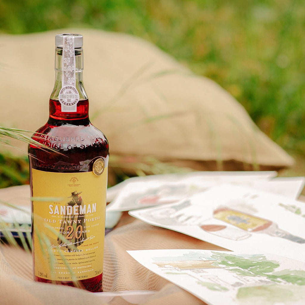Bottle of Sandeman brand wine on a table outdoors with a blurred background