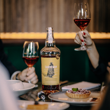 Load image into Gallery viewer, Bottle of Sandeman Port with two glasses and a tart on a table.