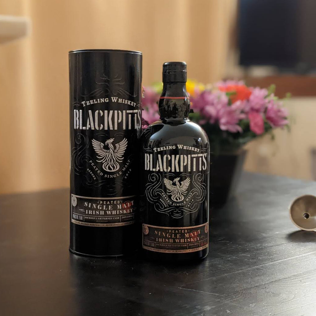 Two bottles of Blackpitts peated whiskey on a table with a blurred background