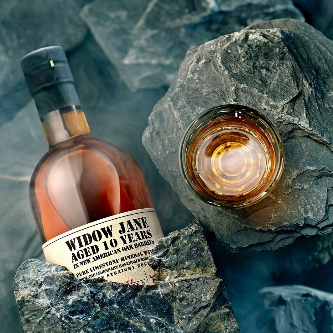 Load image into Gallery viewer, A bottle of Widow Jane 10YO Straight Bourbon hiding behind a rock