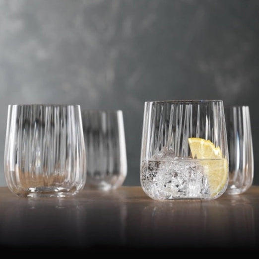 Clear glass tumblers with lemon slices on a dark surface and gray background